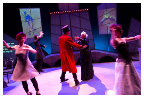 5 actors are spread across the stage dancing as if at an old fashioned ball. Two of them dance together in the middle. They are all in Victorian dress.