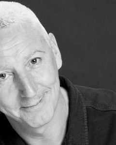 A black and white photo of Kinny Gardner. He has short white hair and a long face. 
