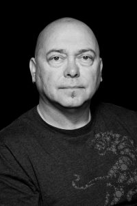 A black and white photo of Garry Robson. He has a round face, no hair and a small black goatee. 