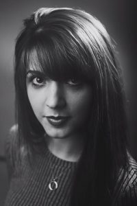 A black and white photo of Lauren Gilmour. She has thick dark hair with a fringe and big dark eyes.