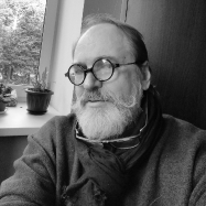 A black and white photo of Victor Nikonenko. he has a long white beard and thin wire framed round glasses. 