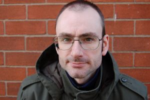 A photo of Douglas Maxwell. He has thinning dark hair and big glasses. 