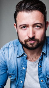 A photo of John McLarnon. He has slicked back black hair and black beard
