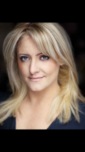 A photo of Louise McCarthy. She has long blonde hair, blue eyes and a tight lipped smile