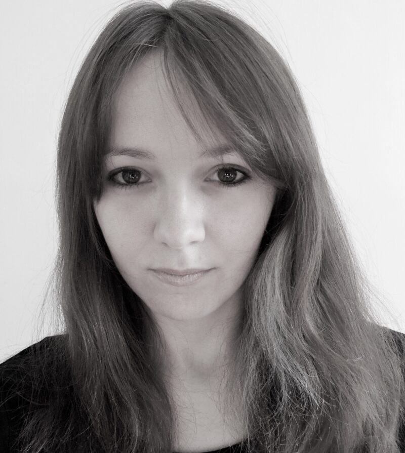 A black and white headshot of a young woman. She has long hair and big eyes.