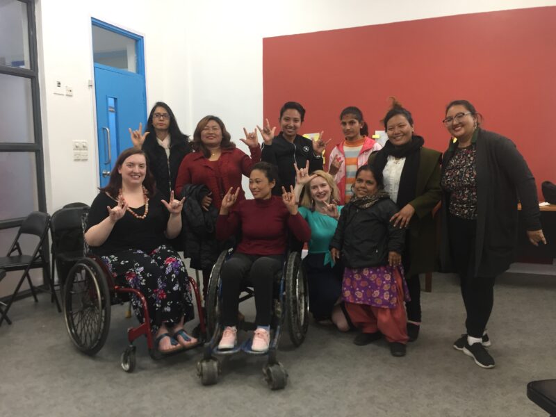 Mairi and Michelle posing with participants from the workshop, doing the Nepalese sign for 'wmoan' on International Women's Day