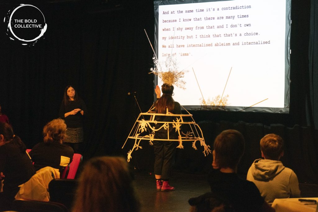 A performer presents a wearable sculpture depicting brain neurons