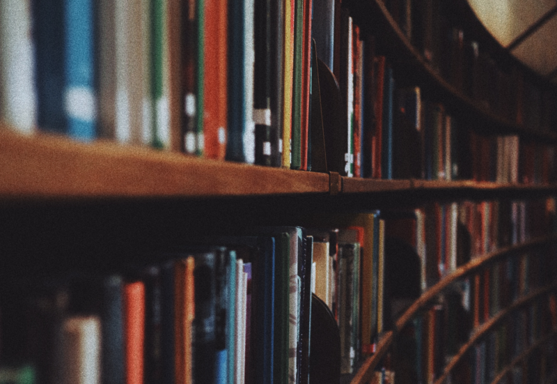 Photo of a large library sized bookshelf taken slightly side on so we can see the curve of the bookshelves as it bends around the large room.