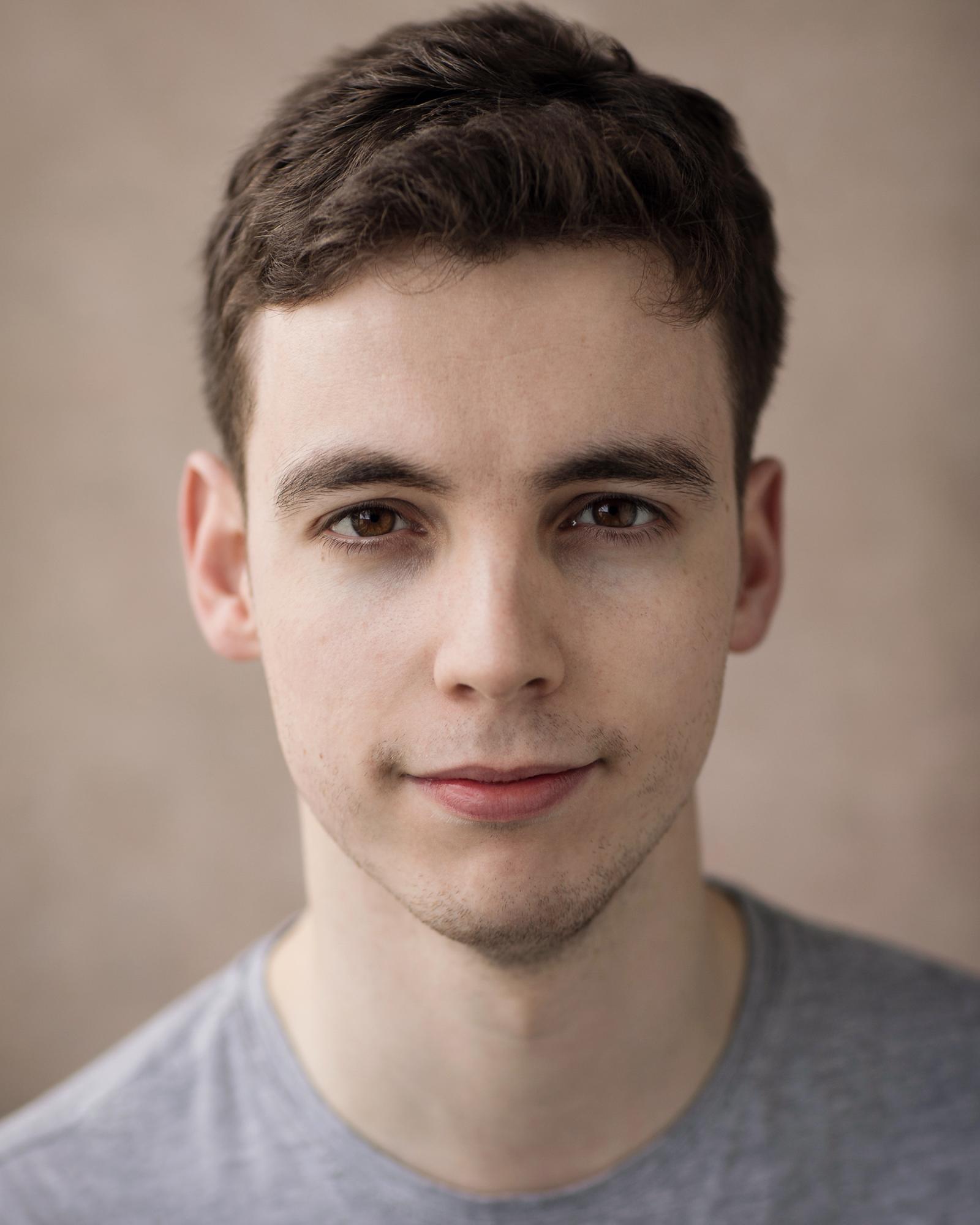 Headshot of Jack Hunter. A white man in his late 20s. Short brown, curlyish hair, with a slight smile.