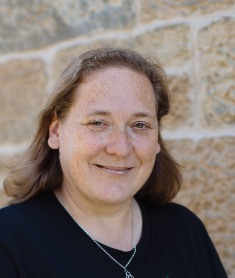 Headshot of Louise, white middle aged woman with shoulder length brown hair, she smiles into camera.