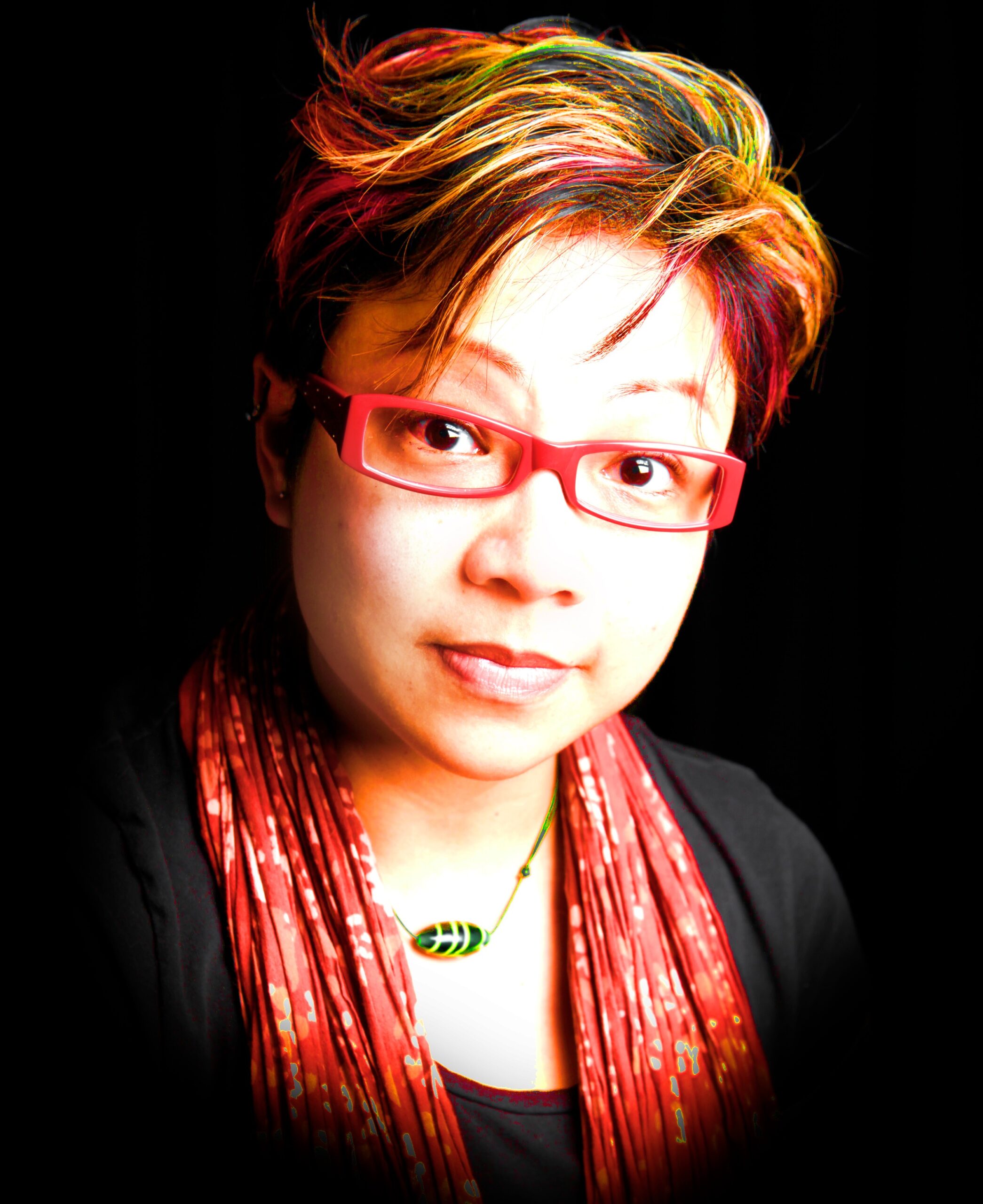 JT is a woman of Chinese heritage in her 40s, with short hair died red and yellow. She had red rimmed glasses and a red top with a black jacket.