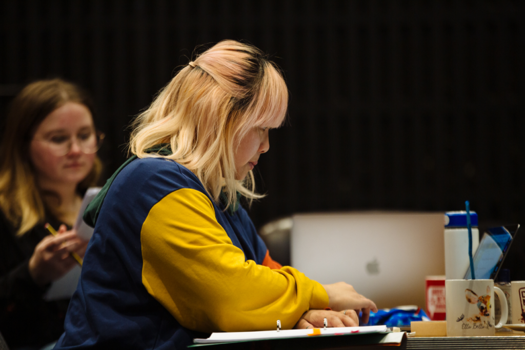 Photo of Cynthia, a Chinese person in their 20s. She is seated at a table and concentrating on a laptop.
