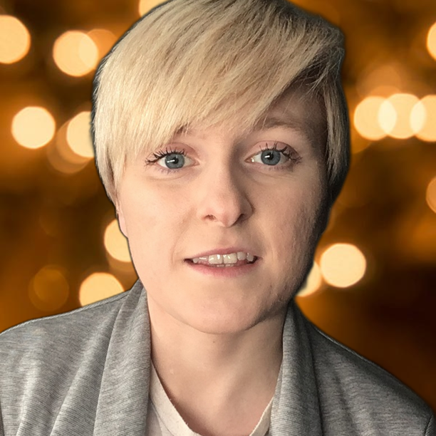 A young person with short blond hair swept to one side, looking out at the camera against a background of blurred lights.